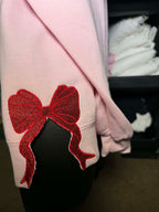 Pink garment with a red bow embroidered on a pink sweatshirt 
