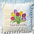 Close up of square-shaped embroidered pillow with a design of pink, yellow, and lavender tulips and the text 'Happy Mother's Day'.