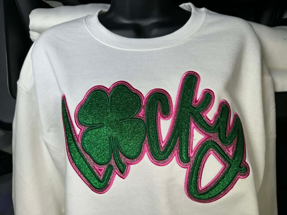 White sweatshirt with green and pink 'Lucky' design on a mannequin.