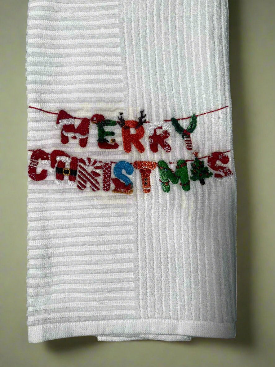 White kitchen towel with colorful embroidered "Merry Christmas" letters on a string
