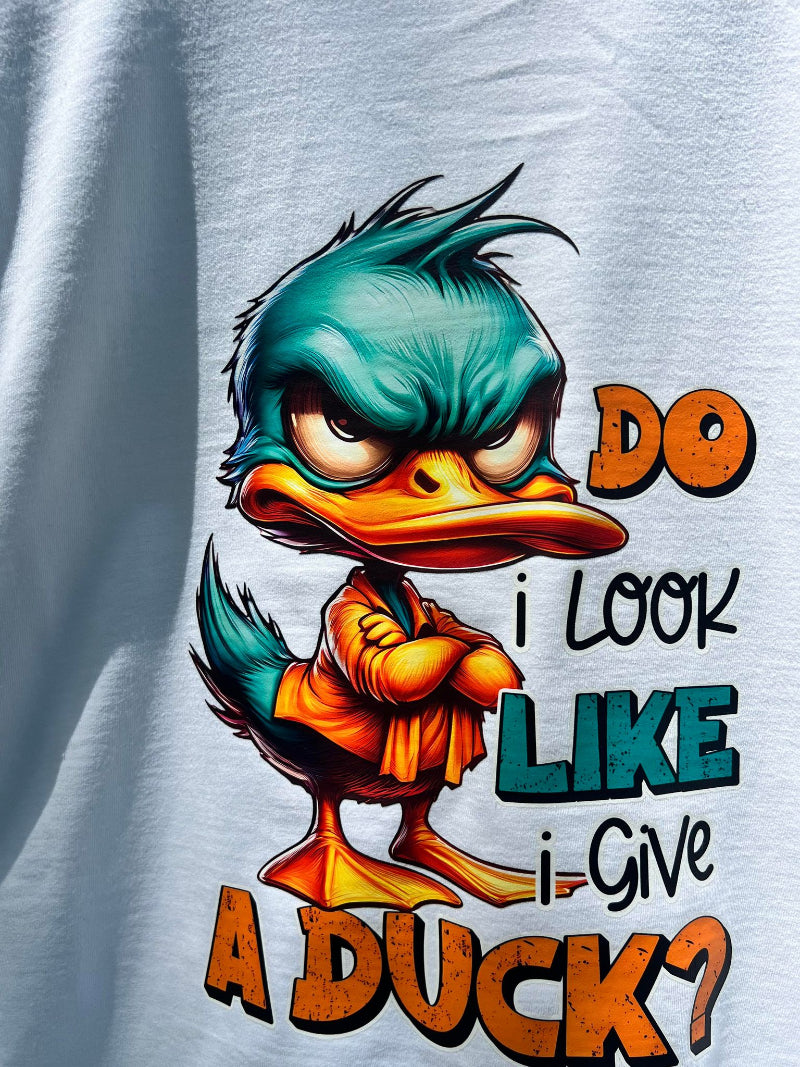 Close-up of duck cartoon with folded arms on Do I Look Like I Give a Duck on white shirt.