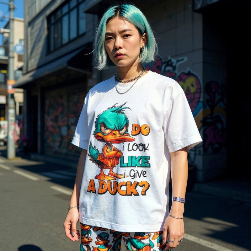 Person wearing a white t-shirt with a cartoon character and text on a street background