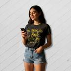 Woman wearing a black t-shirt with yellow text, standing against a light wooden panel background.